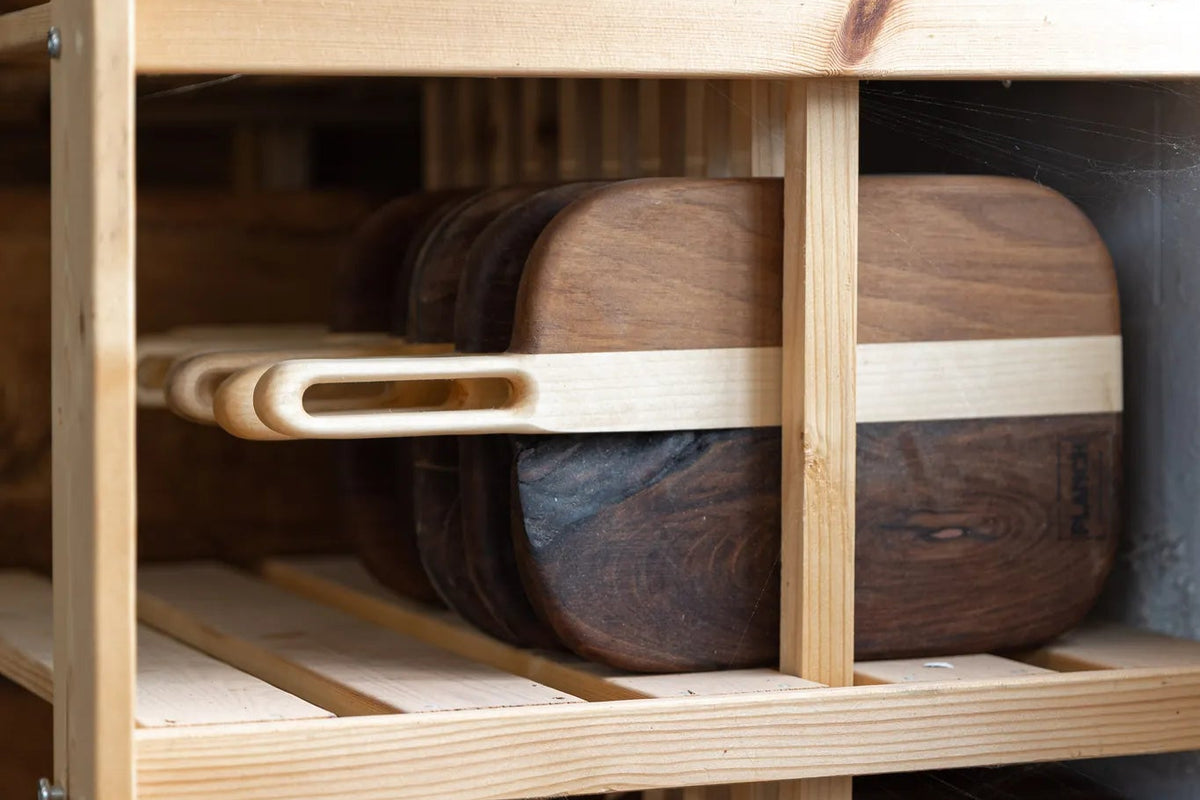 Planches à découper en noyer massif en cours de séchage sur un rack dans l'atelier Planch'h